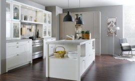 Een eenvoudig kader legt een accent op de mat gelakte fronten en geeft de gehele keuken een burgerlijke en tegelijkertijd klassieke, hedendaagse uitstraling. Cassette fronten met knoppen, glazen deurtjes en een centrale oven/fornuis. Zuordnung: Stil Design-keukens, Planungsart Open keuken (woonkeuken)