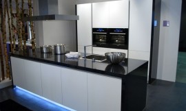 Design keuken met hoogglans zwarte wangen en aanrechtblad. Greeploze fronten en opvallende blauwe verlichting uit de sokkel van het keukeneiland. Zuordnung: Stil Design-keukens, Planungsart Open keuken (woonkeuken)
