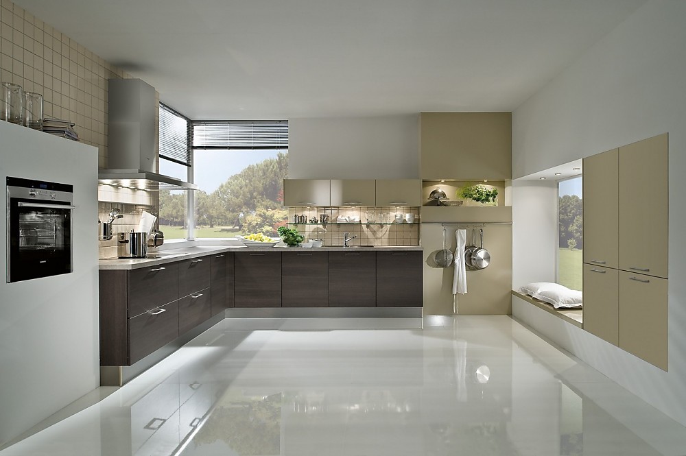 Hier ziet u de keuken reflecteren in een glanzende vloer. Eiken houtdecor fronten gecombineerd met beige (rechts). Zitgelegenheid o.a. op kussens tegen het raam. Zuordnung: Stil Moderne keukens, Planungsart L-vormige keuken