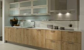 Moderne houten keuken met lichte eiken fronten gecombineerd met dunne witte aanrechtbladen en hangkasten. De deurtjes van de hangkasten zijn voorzien van matglas. Zuordnung: Stil Moderne keukens, Planungsart U-vormige keuken