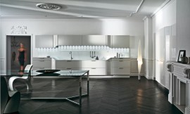 L-keuken met groot, symmetrisch keukenblok. Witte fronten met horizontale grepen. Werkblad met hoogteverschillen en verlichting vanuit de bovenkast. Verschillende rondingen in het kastontwerp. Zuordnung: Stil Design-keukens, Planungsart L-vormige keuken