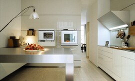Apparatuurkasten kunnen, zoals u hier ziet, ook zwevend aangebracht worden. Deze design keuken heeft opvallend slanke fronten en aanrechtbladen, en een bijzondere driehoekige afzuigkap. Zuordnung: Stil Luxe keukens, Planungsart Keuken met keukeneiland