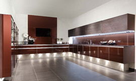 De keuken als zwevend element in de ruimte. Spanningsvolle architectuur in vorm en kleur. Achter glas de trendkleur robijn metallic. En als uniek kenmerk het variabele kastsysteem "Volare" met schuifdeuren van echte leisteen. Zuordnung: Stil Design-keukens, Planungsart U-vormige keuken