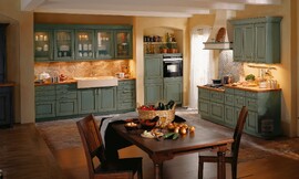 Rustieke landelijke keuken met ingemetselde afzuigkap. Opvallend hoge gootsteen en bovenkasten met glazen deurtjes. Vele ornamenten sieren deze landelijke keuken. Ook de vloer is voorzien van een bijzonder patroon. Zuordnung: Stil Landelijke keukens, Planungsart L-vormige keuken