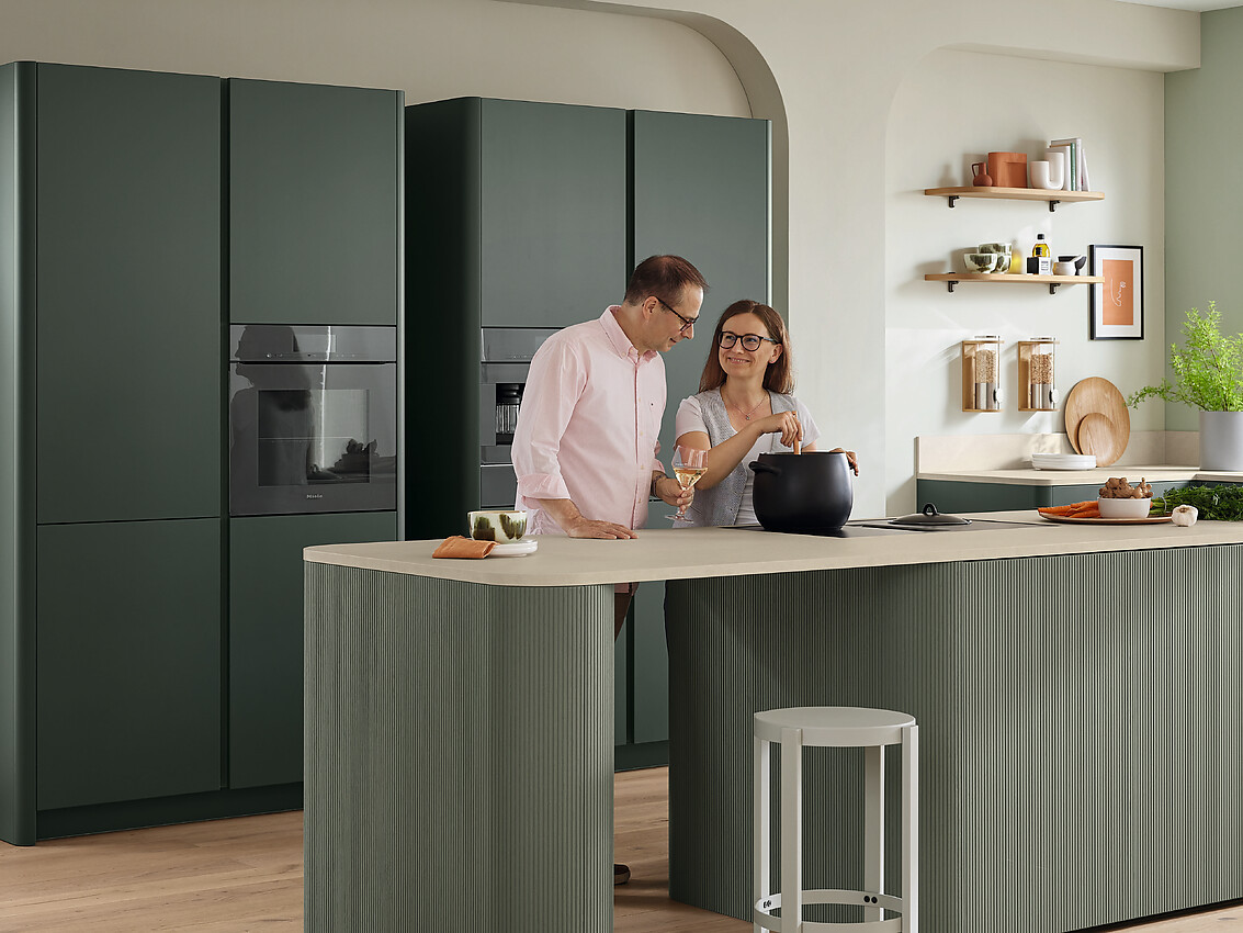 Met Savona-groen en Night Green kiezen we voor een groene keuken die rust en levensvreugde uitstraalt. Het Talea-front in Savona-groen en de hoogwaardige fluweellak Night Green vullen elkaar toon op toon aan. Zachte rondingen geven het kookeiland en de eindpanelen een huiselijk, organisch karakter. Zuordnung: Stil Moderne keukens, Planungsart Keuken met keukeneiland