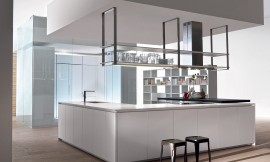 Dit geruime kookeiland wordt gesierd door een open servieskast die aan het plafond hangt. Door greeploze fronten domineren rechtlijnigheid en lichte kleurtinten. Hier ziet u ook wat er in een ruimte met een hoog plafond gedaan kan worden middels een plafondverlaging. Zuordnung: Stil Design-keukens, Planungsart U-vormige keuken