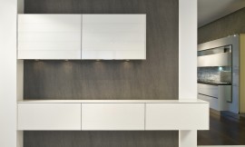 Detail van de witte nagkasten. De wanden van de kast zijn subtiel dun en de fronten greeploos. In de bovenkast zitten spots. Subtiel contrast met de bruingrijze achterwand. Zuordnung: Stil Moderne keukens, Planungsart Detail keukenontwerp