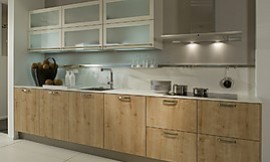 Moderne houten keuken met lichte eiken fronten gecombineerd met dunne witte aanrechtbladen en hangkasten. De deurtjes van de hangkasten zijn voorzien van matglas. Zuordnung: Stil Moderne keukens, Planungsart keukenblok