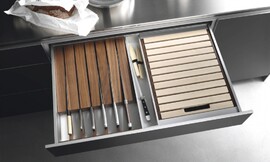 Speciale lade om uw messen beschermd en uit het zicht op te bergen. Hier uitgevoerd in een keukenkastje met metallic tinten en een rvs-aanrechtblad. Zuordnung: Stil Design-keukens, Planungsart Keuken met zitgelegenheid